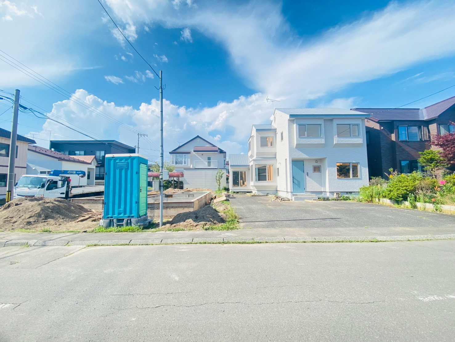 正面から見た改修後の住宅。白い外壁と青い玄関ドア
